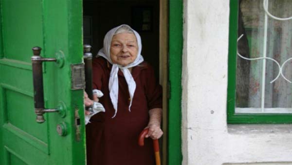 старая женщина выходит через зелёную дверь