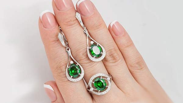 серьги и кольцо на руке с зелёным камнем